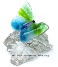 Speels groen en aqua vlinder op doorzichtig glasbrok