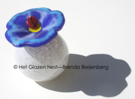 Glazen bol-urn met lieveheersbeestje op bloem