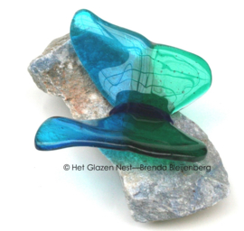 Blauwgroene glazen vlinder op blauwe steen