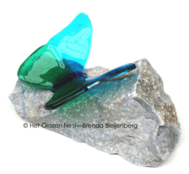 Blauwgroene glazen vlinder op blauwe steen