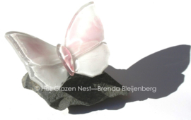 Wit en roze glazen vlinder op basalt