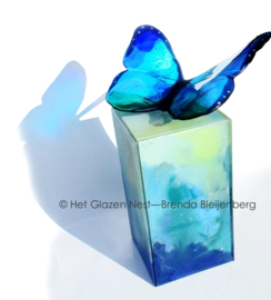 Blauwe vlinder op zee groene urn zuil