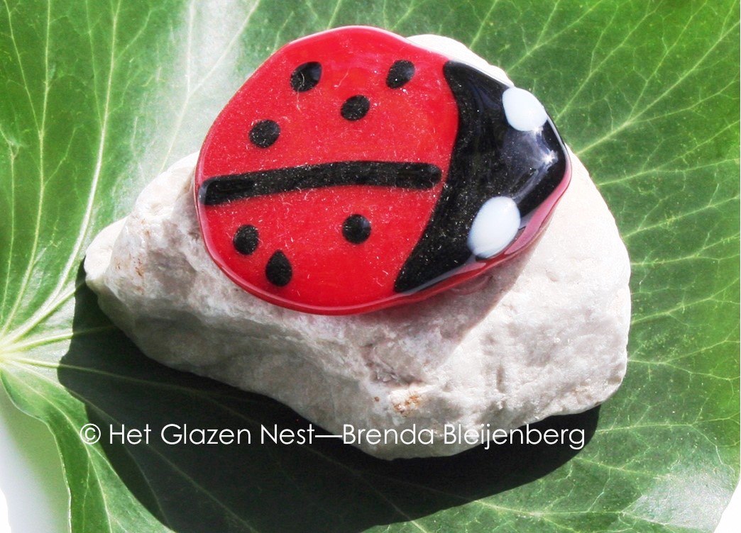Glazen lieveheersbeestje op steentje