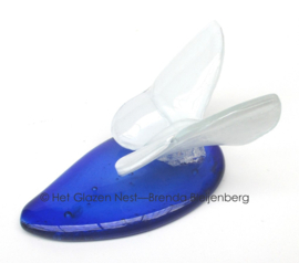 Witte vlinder op blauwe druppel van glas
