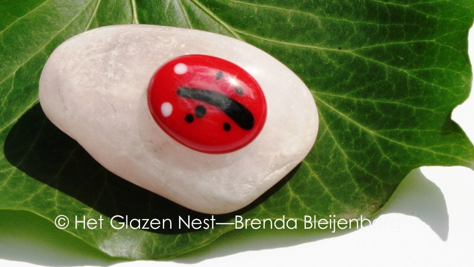 Glazen lieveheersbeestje op calciet knuffelsteen