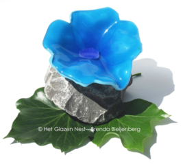 speelse abstract bloem in aqua blauw glas op steen