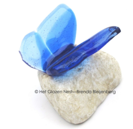 Blauw vlindertje van glas op witte steen