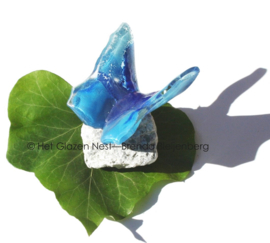 Blauwe vlinder van glas op steentje