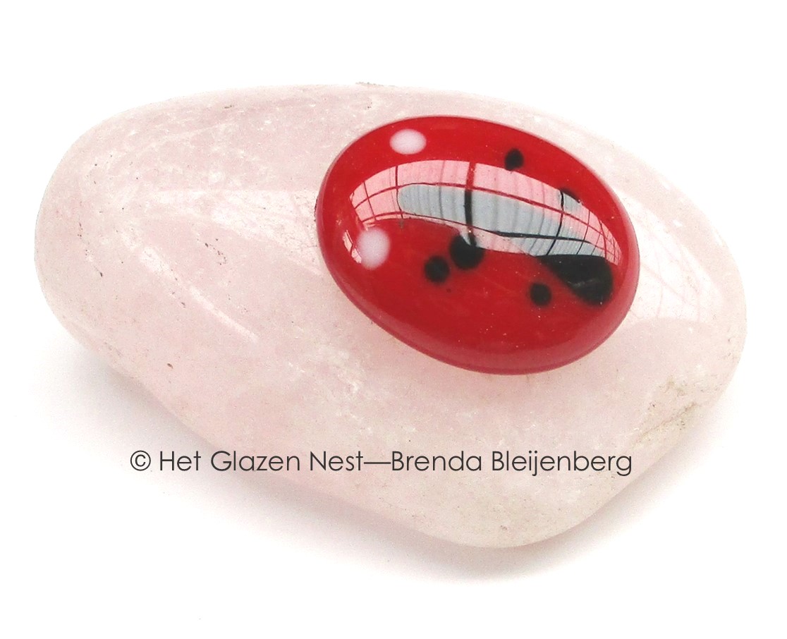 Glazen lieveheersbeestje op calciet knuffelsteen