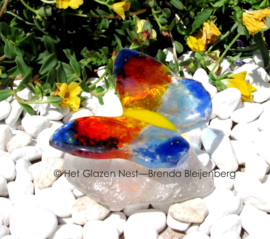 kleine kleurige vlinder op hand gevormde glas steen