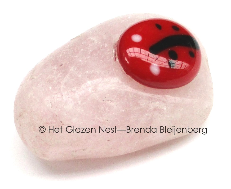 Glazen lieveheersbeestje op calciet knuffelsteen