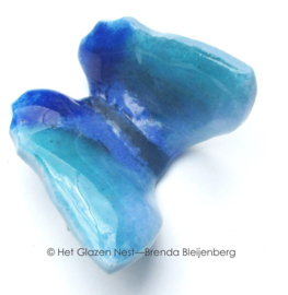 Kleine speelse vlinder in groenblauw glas