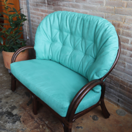 Vintage rotan bank met turquoise kussens
