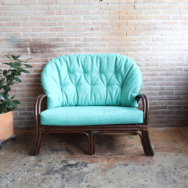 Vintage rotan bank met turquoise kussens