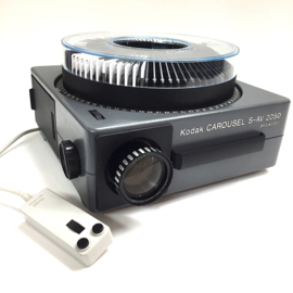 Nr.88705 - mooie KODAK Carousel S-AV 2050 zware projector voor kleinbeeld dia's (5x5cm) met Kodak vario Retinar zoomlens 70 - 120mm  lens ,halogeenlamp 24V-250W.met afstands bediening en carousel , heeft service beurt gehad en is in prima staat