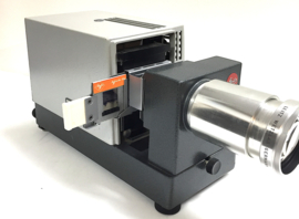 Nr.8144 -- prachtige  Leitz Prado Universal , kleinbeeld ( 5x5 cm )dia projector met zware Halogeenlamp Lamp: 24V 250W  Lens: Leitz Wetzlar Elmaron 2,8/150mm  met kleinbeeld dia houder, is in perfecte staat heeft service beurt gehad en werkt goed.