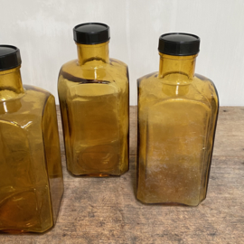 OV20110769 Set of 4 old square French stock bottles of mouth-blown (in mould) glass in beautifully weathered amber colour, all 4 in perfect condition! The screw caps are made of bakelite content: 1000 ml. Size: 21 cm. high / 9.5 cm. wide