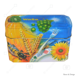 Orange mit blauer Blechdose von Wasa für Knäckerbröd mit einem Bild von Hahn, Biene, Sonnenblume, Getreide und Früchten