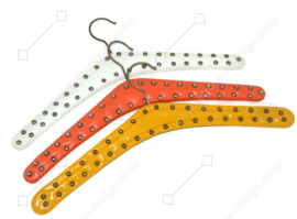 Set van drie vintage Skai kledinghangers in wit, oranje en geel met metalen studs