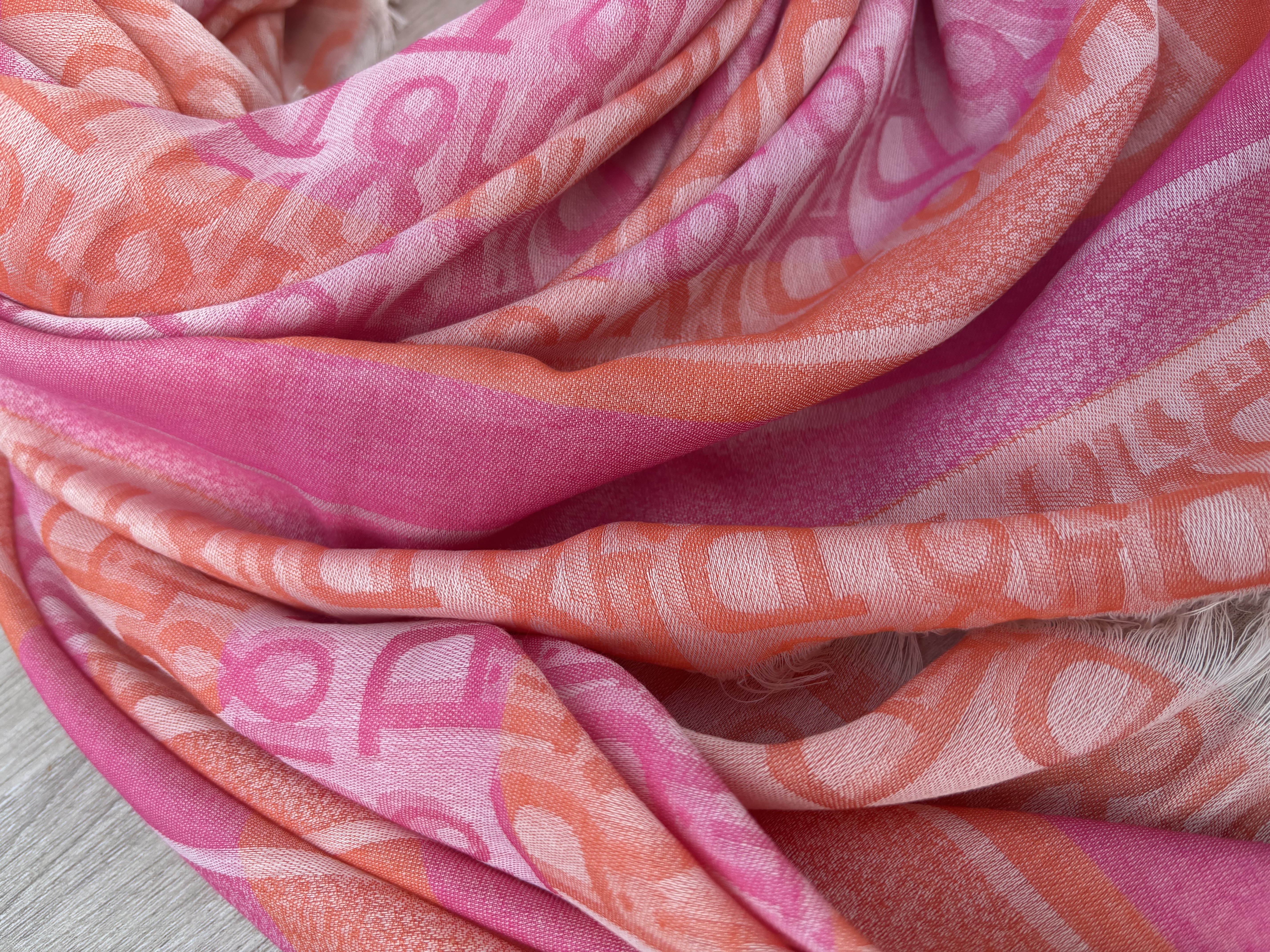 Luchtige dunne sjaal, vierkant. Roze - oranje met letters.