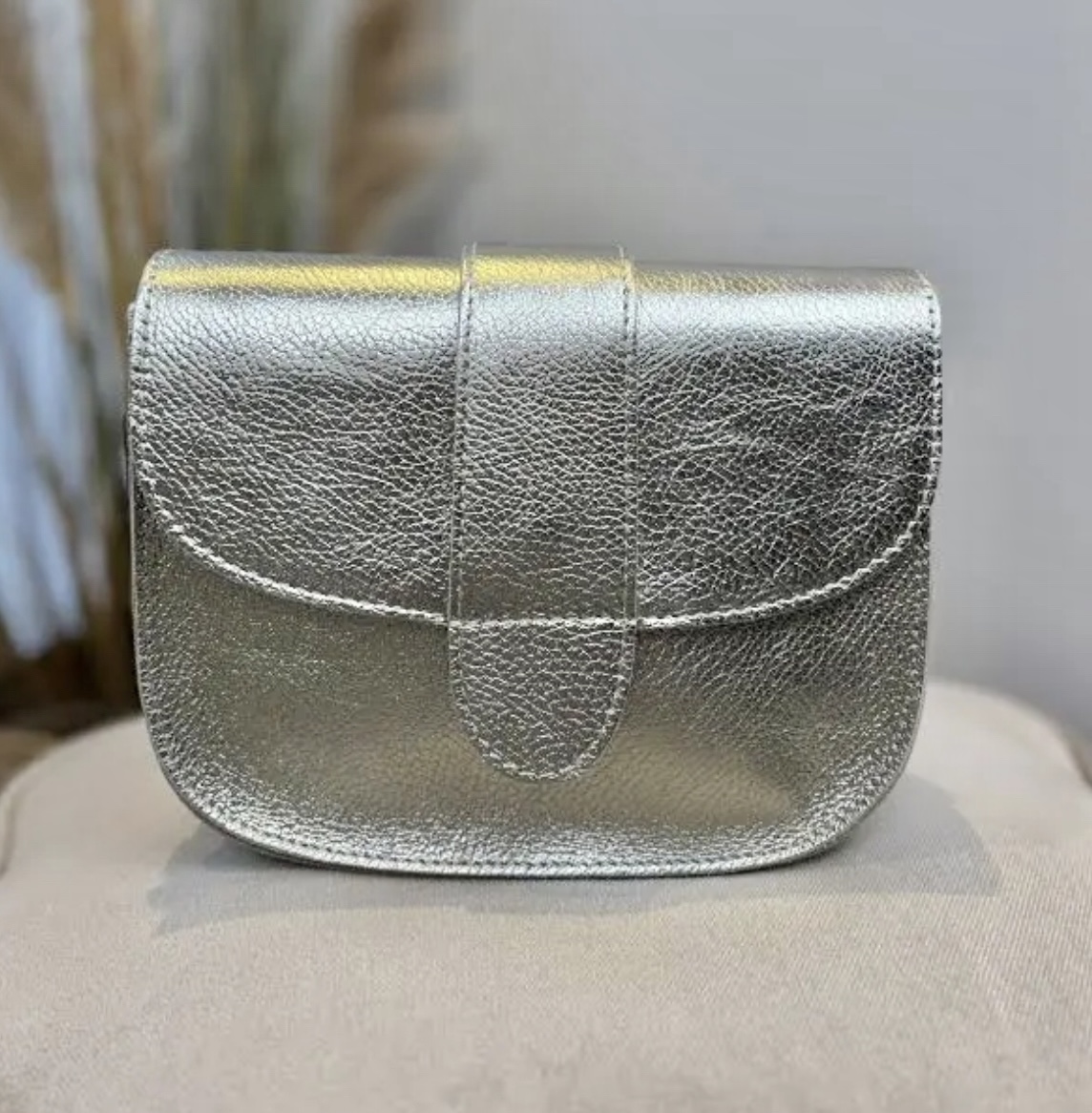 Leren tas met halfronde klep. Licht goud.