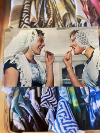 Briefkaarten | Zeeland | Walcheren 1960 -  Fotokaart - Twee vrouwen eten een Zeeuws koekje 'Kanten mutsen met oorijzers'