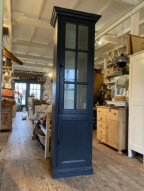 Smalle zwarte vitrinekast met onderkast.