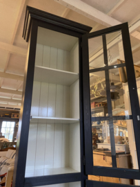 Smalle zwarte vitrinekast met onderkast.