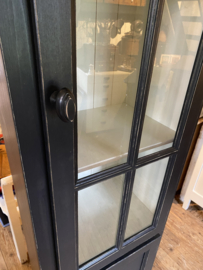 Smalle zwarte vitrinekast met onderkast.