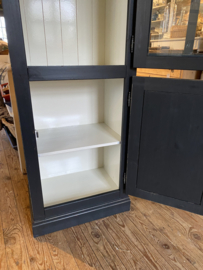 Smalle zwarte vitrinekast met onderkast.