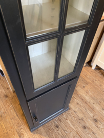 Smalle zwarte vitrinekast met onderkast.