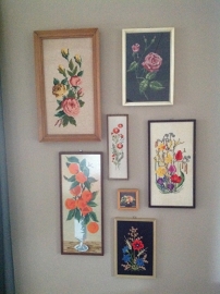 Collage van borduursels aan de wand.