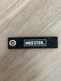 Donkergrijs MEESTER. Vilten Sleutelhanger Klas