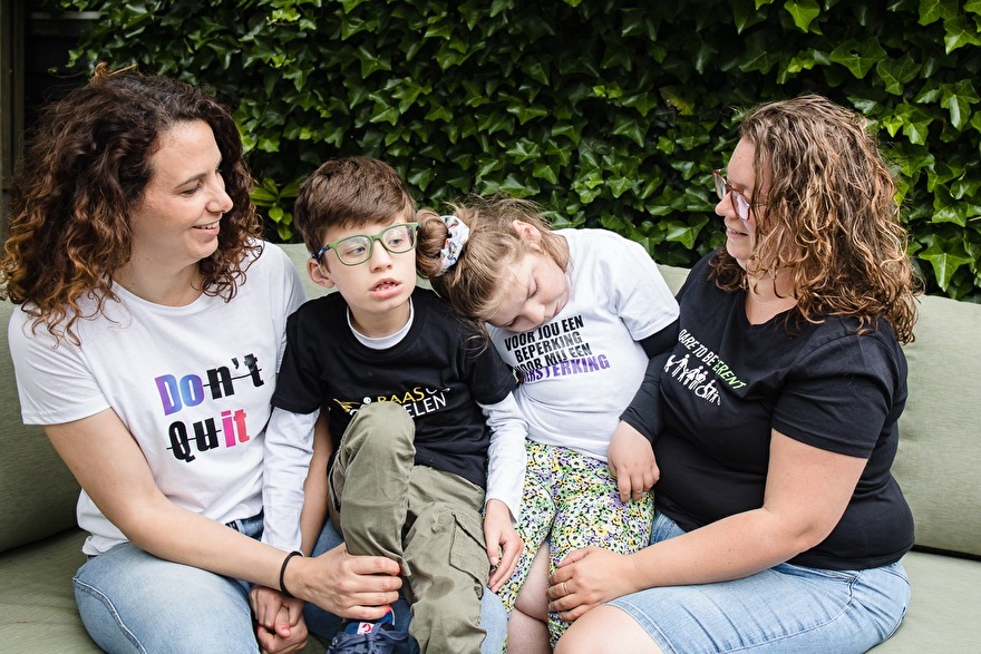 Twee vouwen, moeders met hun twee gehandicapte kinderen. ze dragen t-shirts met teksten erop.