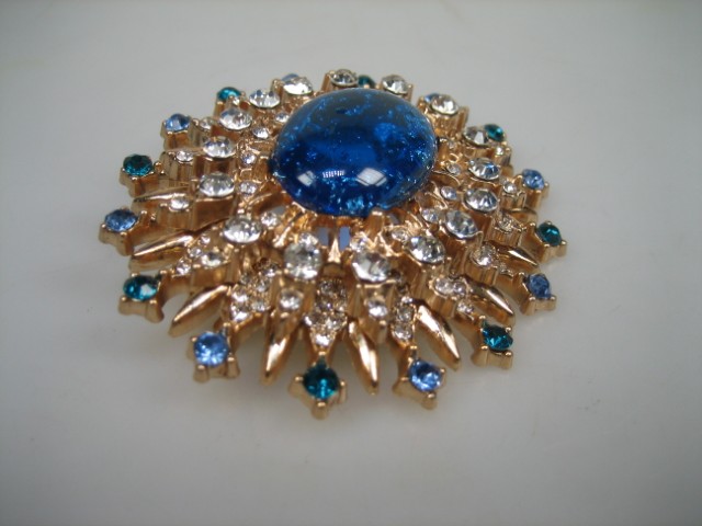 Broche met Blauwe synthetische steen rond gezet met heldere witte en blauwe glasstenen