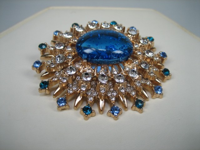 Broche met Blauwe synthetische steen rond gezet met heldere witte en blauwe glasstenen