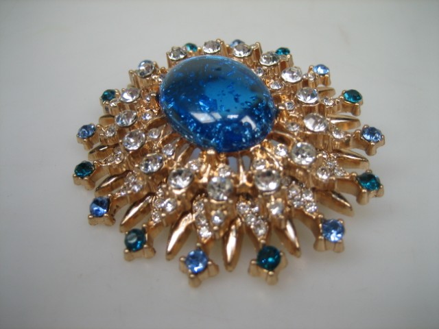 Broche met Blauwe synthetische steen rond gezet met heldere witte en blauwe glasstenen