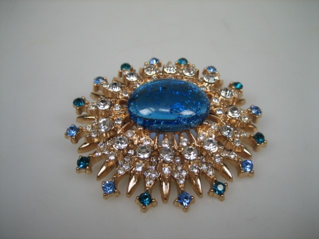 Broche met Blauwe synthetische steen rond gezet met heldere witte en blauwe glasstenen