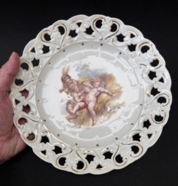 Antique reticulated porcelain plate with three cherubs in hay