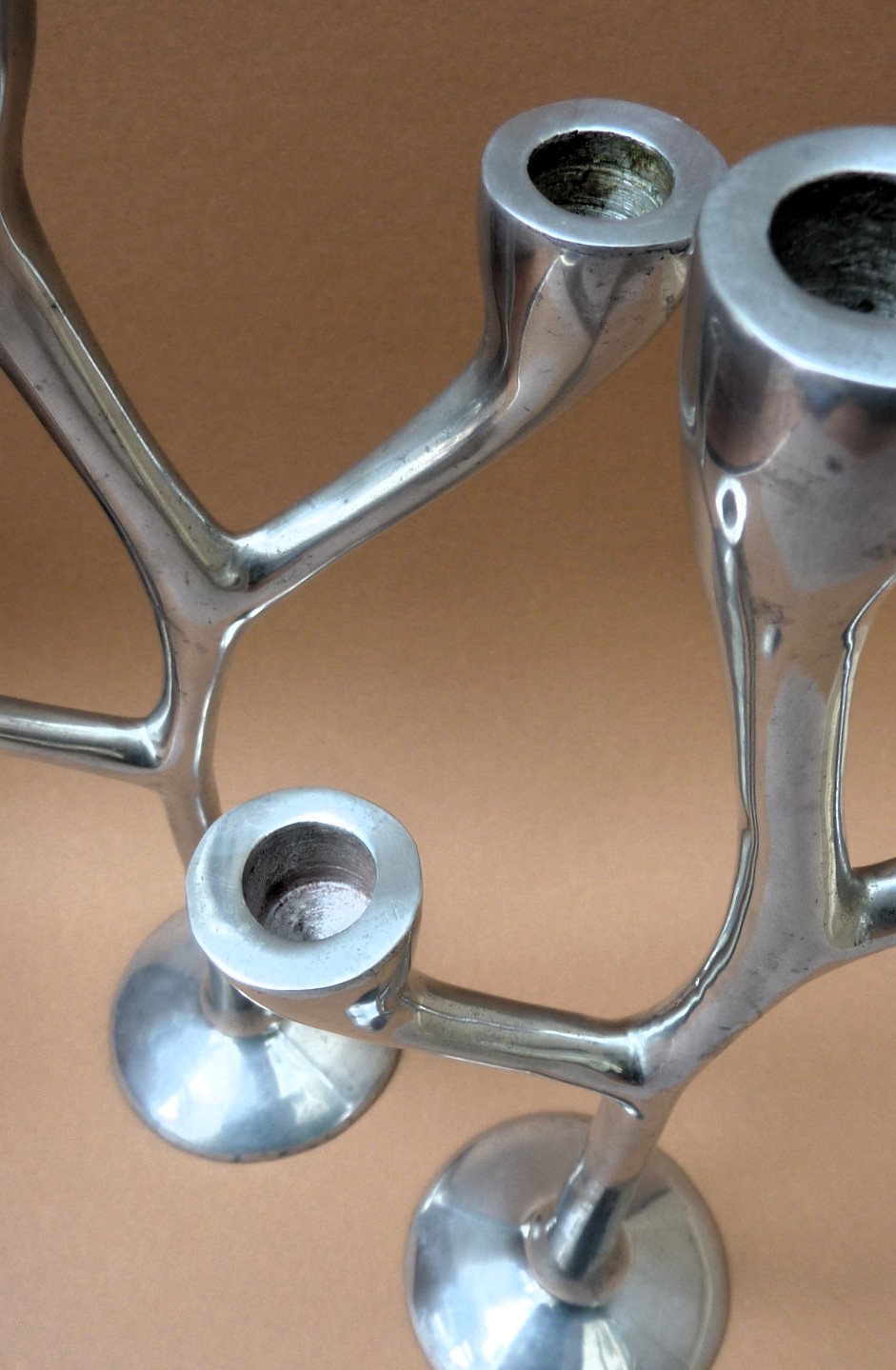 Een paar drie armige aluminium design kandelaars