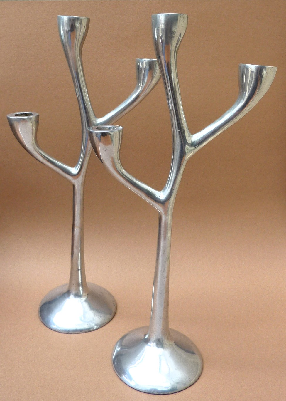 Een paar drie armige aluminium design kandelaars