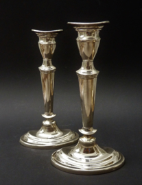 A pair of white metal neo classical style candlesticks