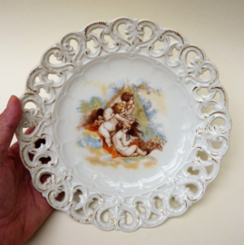 Antique reticulated porcelain plate with playing cherubs