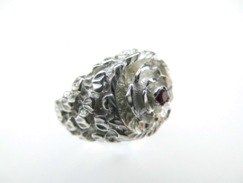 Zilveren bloem op piet-piet ring met rood steentje.
