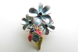 Broche lieveheersbeestje op blauwe bloem.