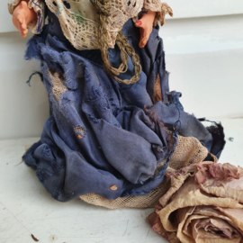 Heel oud popje met versleten blauwe jurk