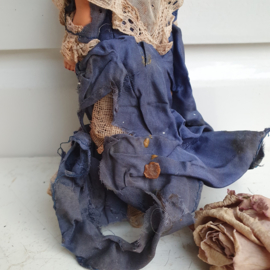 Heel oud popje met versleten blauwe jurk