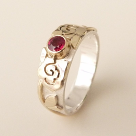 Zilveren ring met geelgouden rozenpatroon en facet geslepen robijn