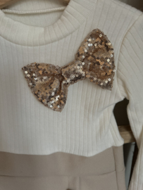 Feestjurk met gouden strik en goudkleurig tasje .