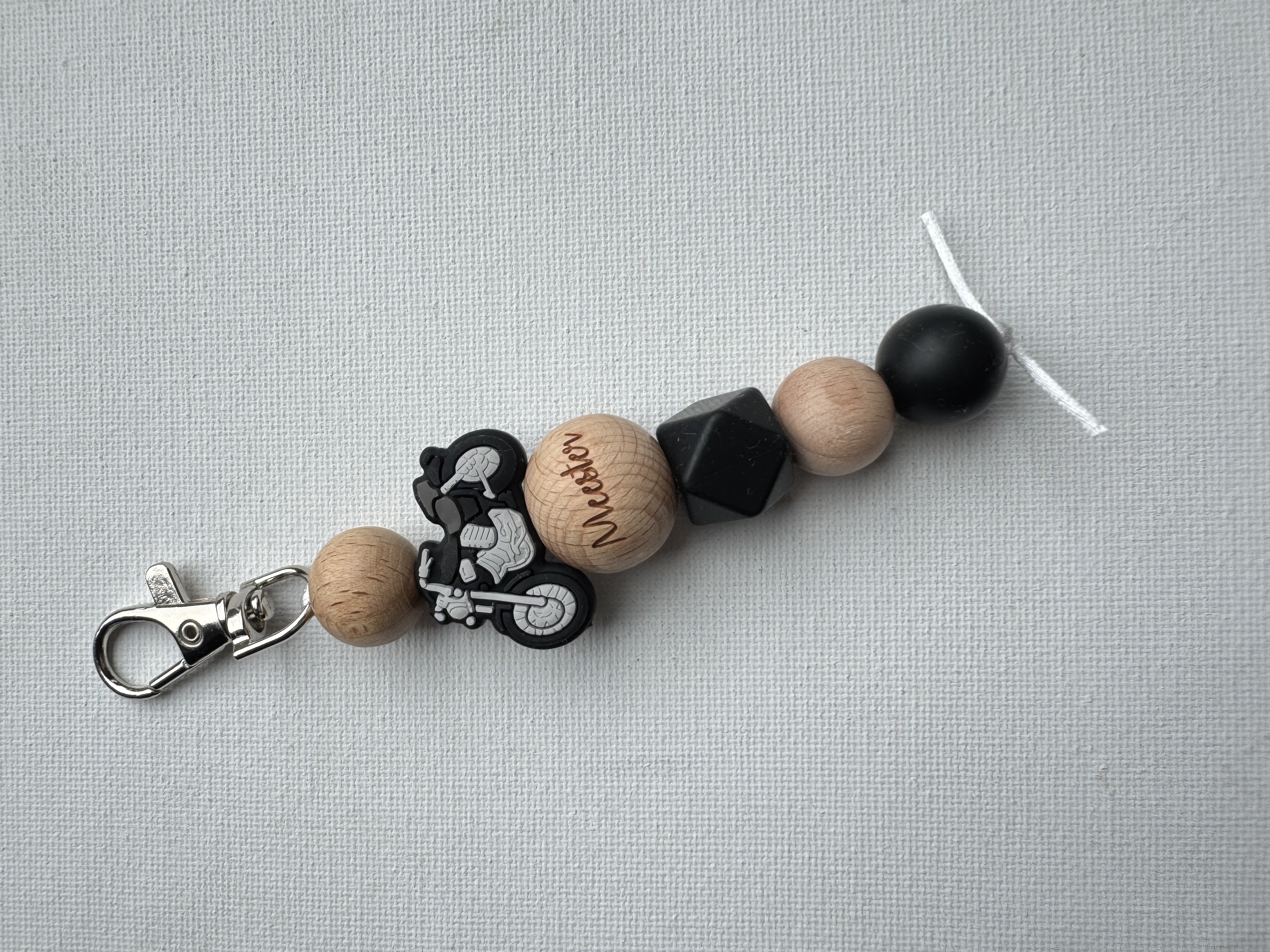 Sleutelhanger meester met een stoere motor in zwart -grijs -hout .